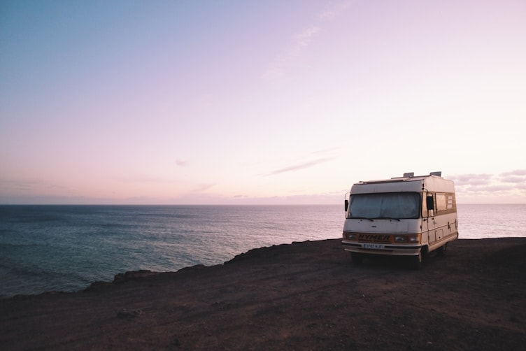 A motorhome parked on a clifftop above the sea at dusk