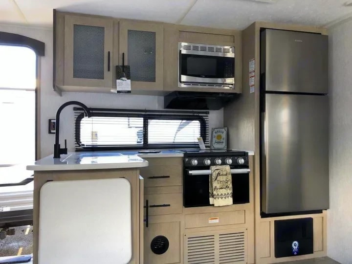 Kitchen counter with sink, cabinets, range, and tall stainless refrigerator