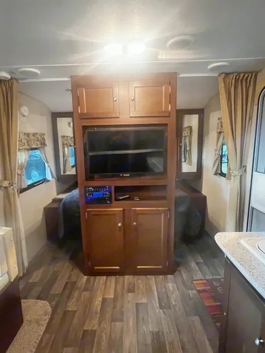 Bedroom entertainment center with mounted TV and cabinet storage above the bed