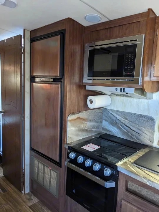 Close view of the refrigerator, stovetop, and overhead microwave