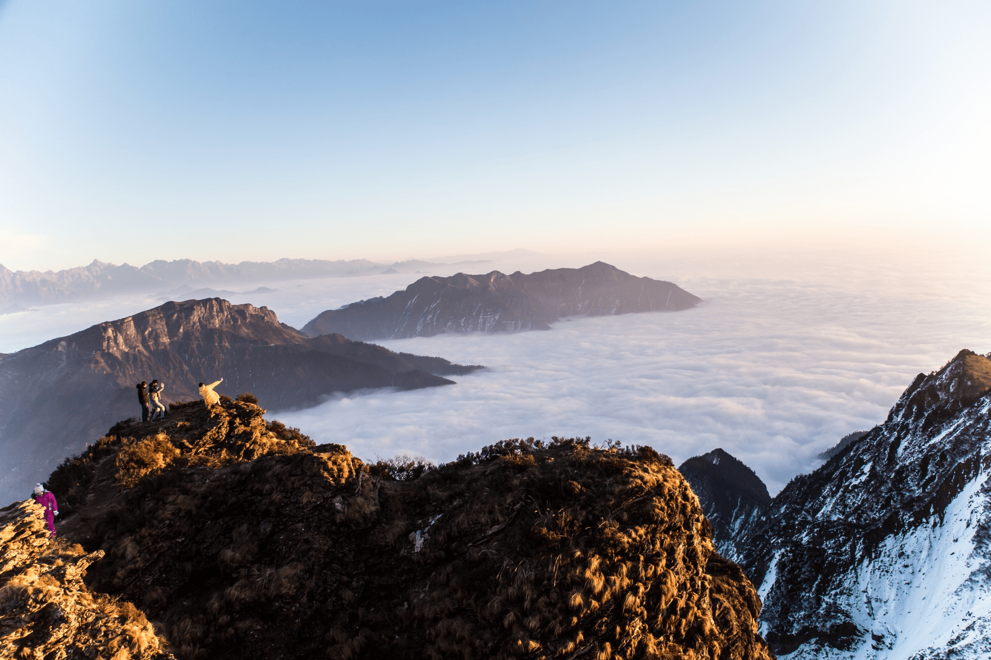 Hikers above a sea of clouds at sunrise