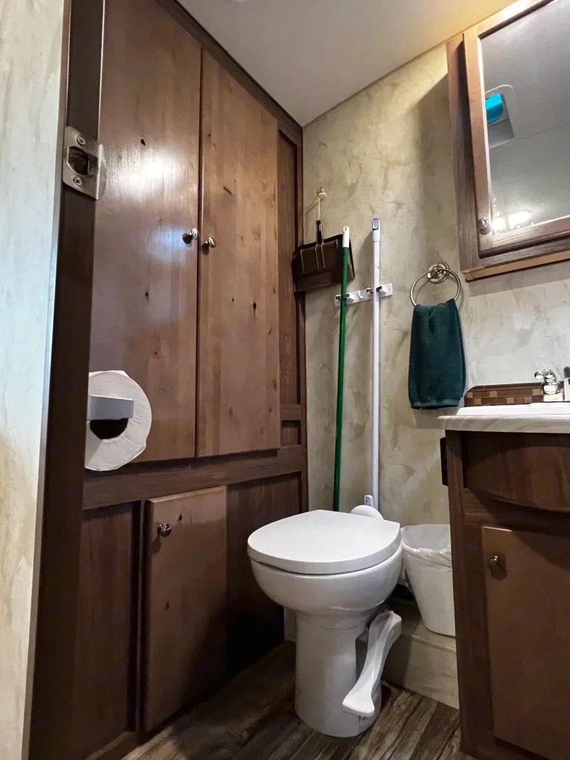 Bathroom toilet and tall wood storage cabinet with towel ring