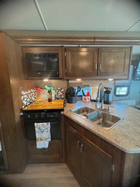 Kitchen stove and built-in microwave with cutting board on the counter