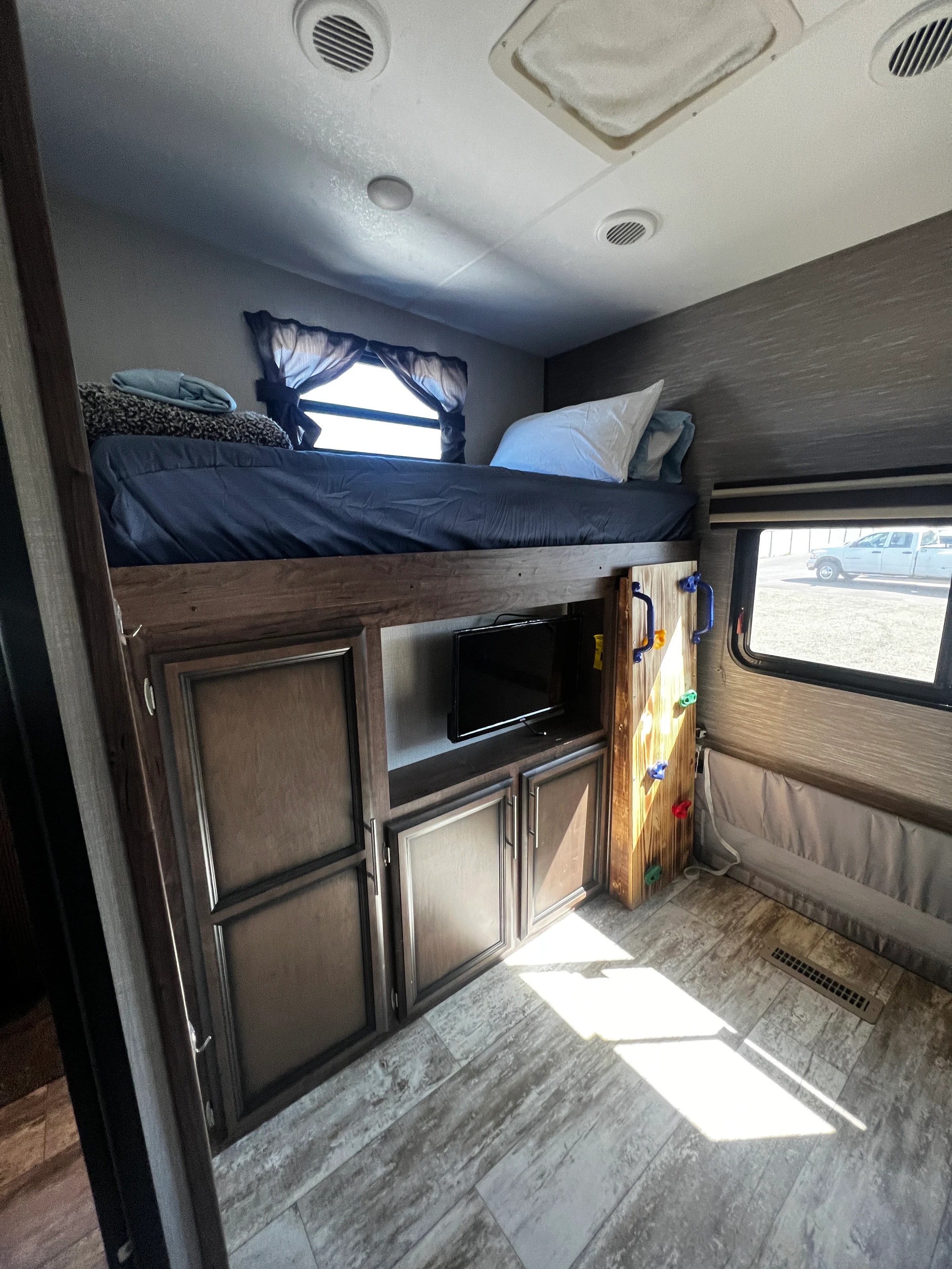 Loft bunk over built-in cabinets with a TV nook, near a window