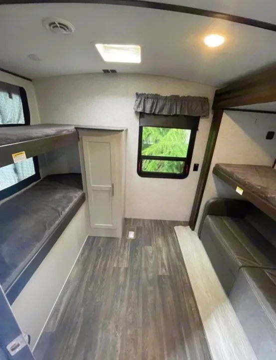 Bunk beds and bench seating in the bunkhouse with window and wood-look flooring