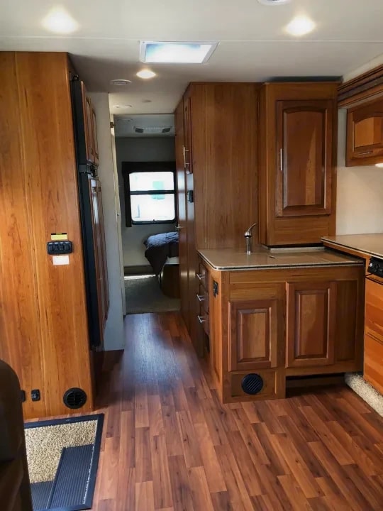 Kitchen area with wood cabinetry, sink, and hallway toward the bedroom