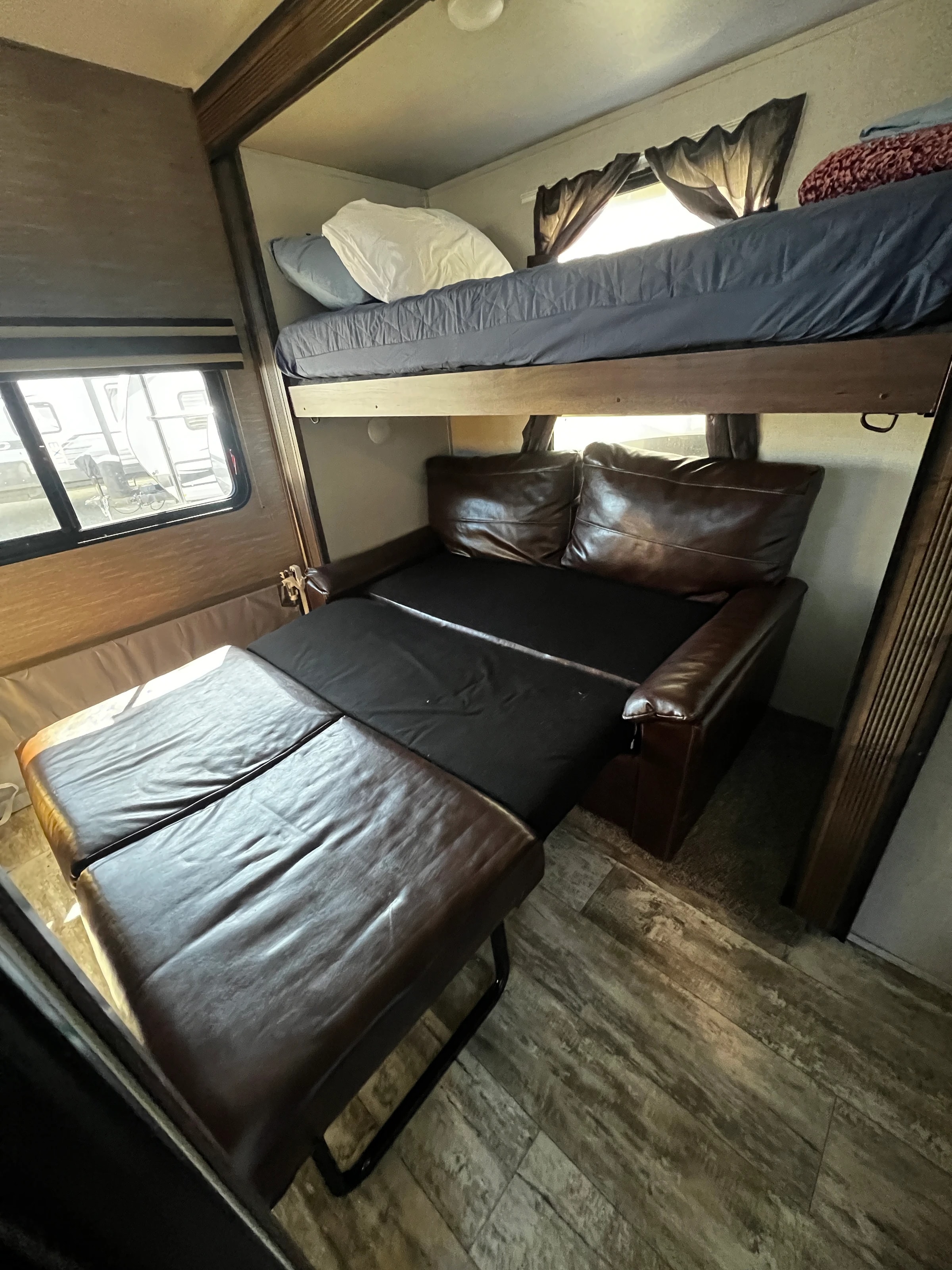 Bunk bed over a jackknife sofa with the window curtain open