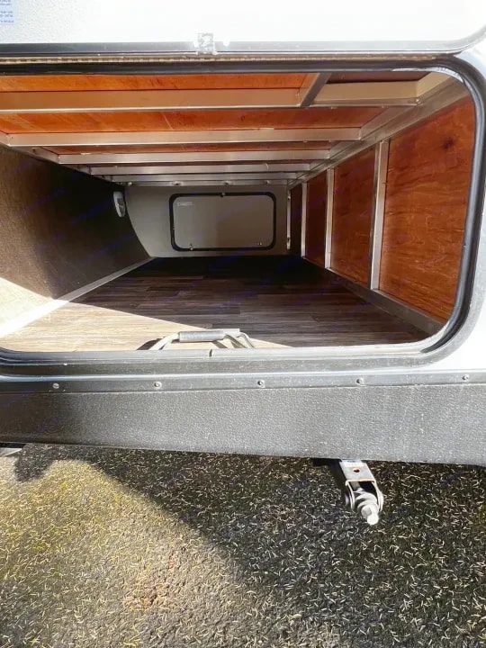 Empty underbody storage compartment viewed from the open door