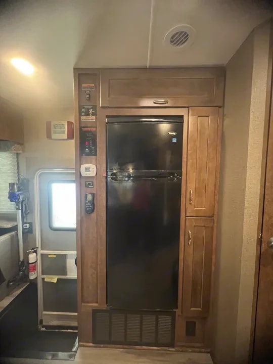 Built-in refrigerator flanked by wood cabinetry