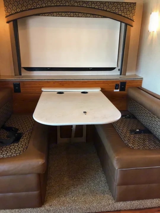 Dinette booth with leather bench seating and drop-leaf table, pull-down screen above