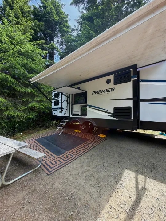 Side view under the awning showing entry door, steps, and outdoor rug