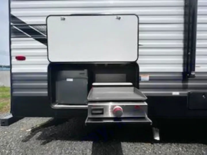 Exterior pass-through storage compartment with fold-out griddle and fridge