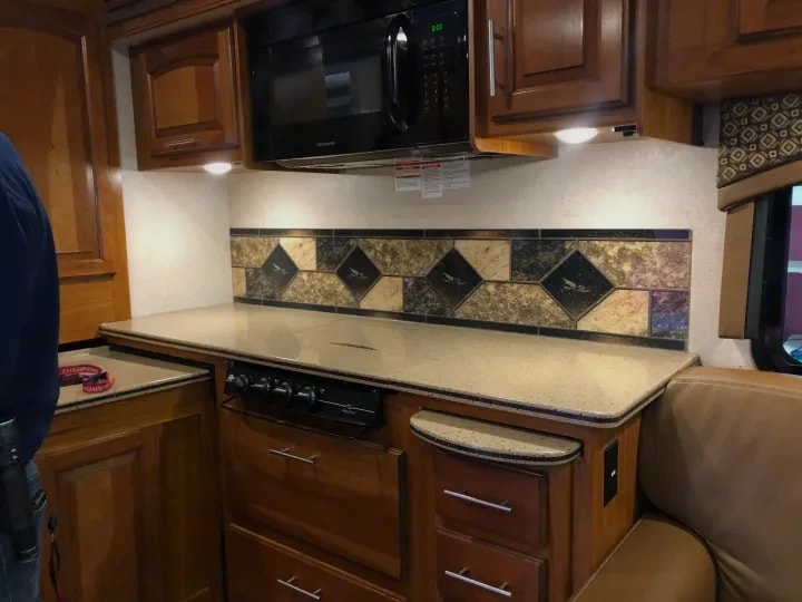 Kitchen counter with overhead microwave and tiled backsplash