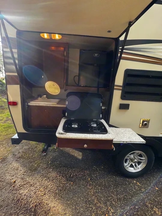 Open pass-through outdoor kitchen with sink, small fridge and fold-out stove