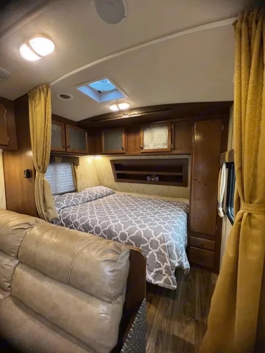 Bedroom nook with skylight, overhead cabinets, and adjacent leather sofa