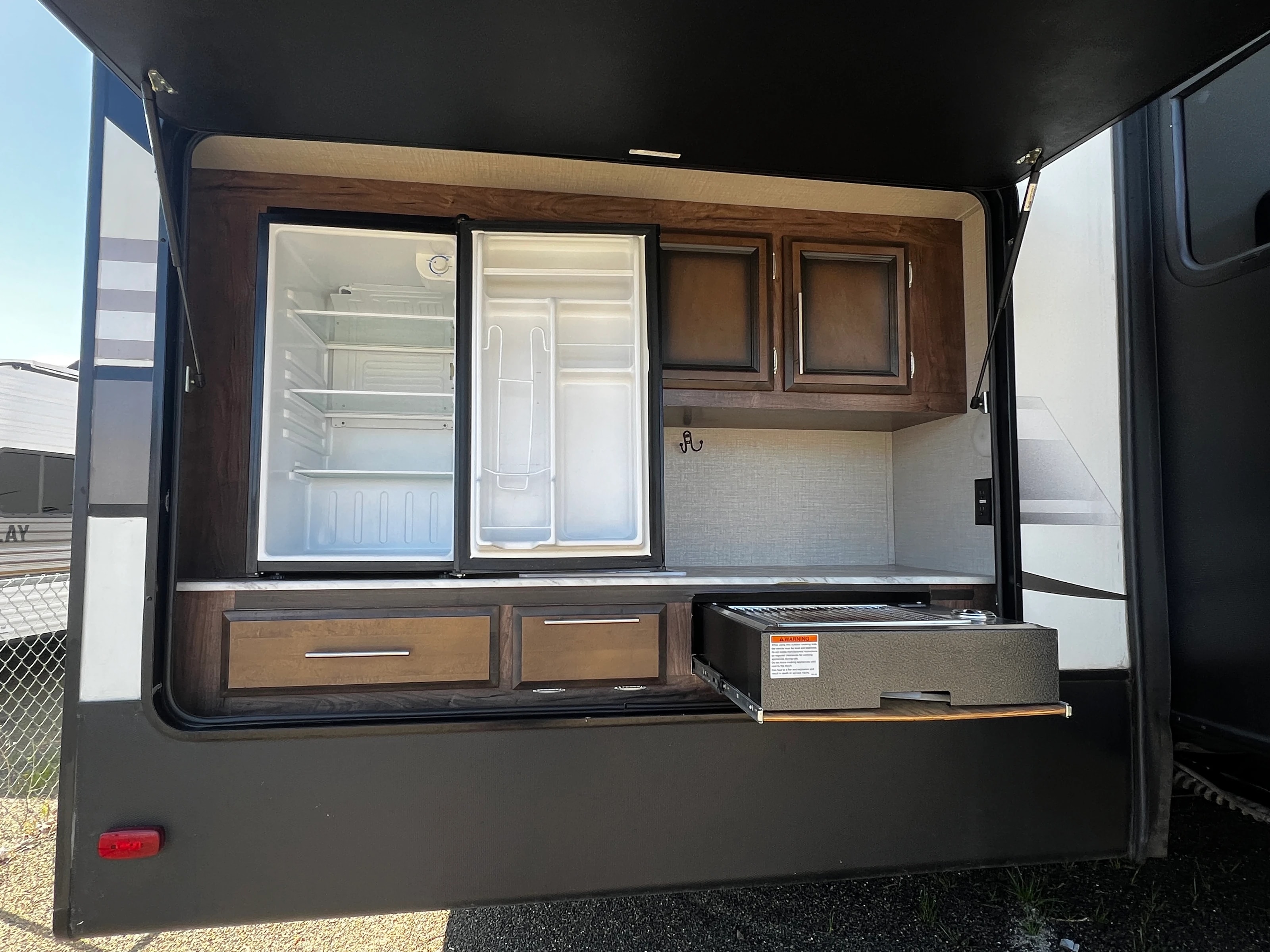 Open pass-through outdoor kitchen with mini fridge and storage cabinets