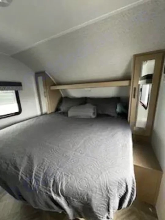 Bedroom with made queen bed and built-in wardrobe with mirror
