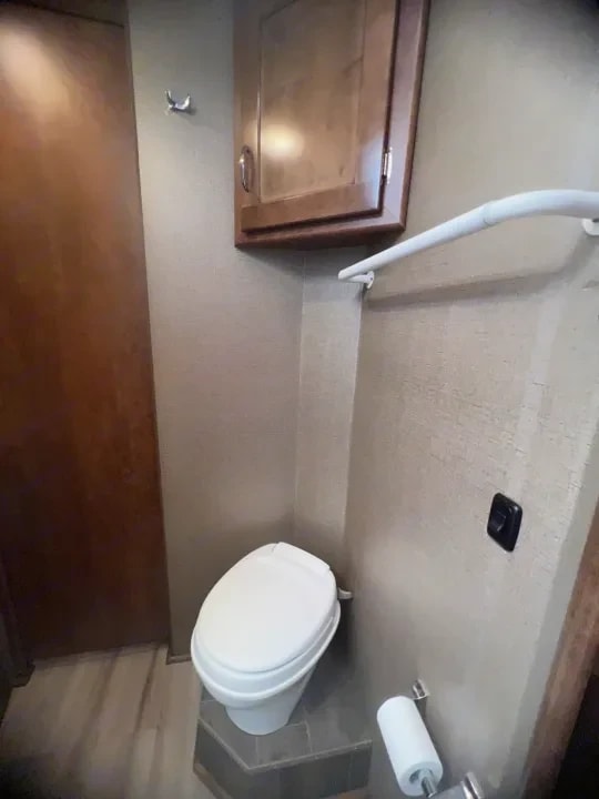 Toilet with overhead cabinet and shower curtain rail