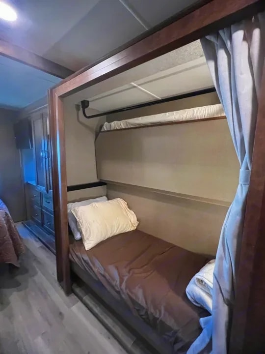Twin bunk beds with pillows and a privacy curtain