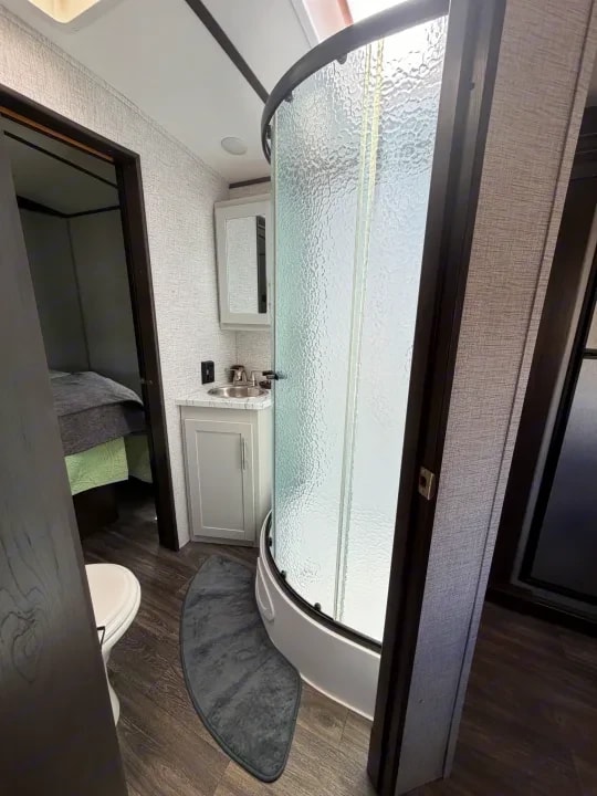 Bathroom sink and shower with bedroom visible through the doorway