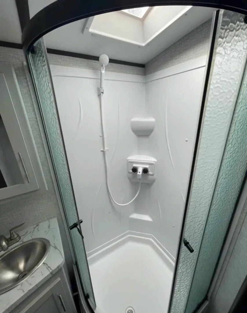 Corner shower stall with skylight, handheld sprayer, and frosted glass doors