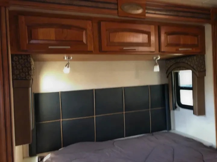 Bedroom headboard area with overhead cabinets and reading lights above the bed