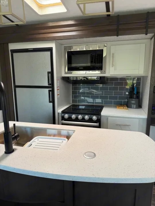 Kitchen with refrigerator, microwave, tile backsplash, and cooktop range