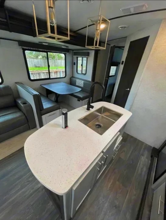 Kitchen island sink with dinette, sofa, and door in the background