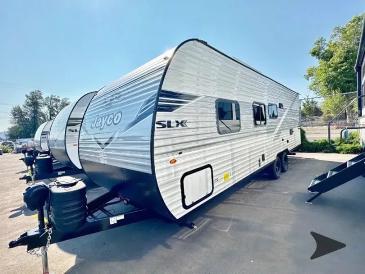 Side profile exterior view of the trailer parked in a row with other RVs