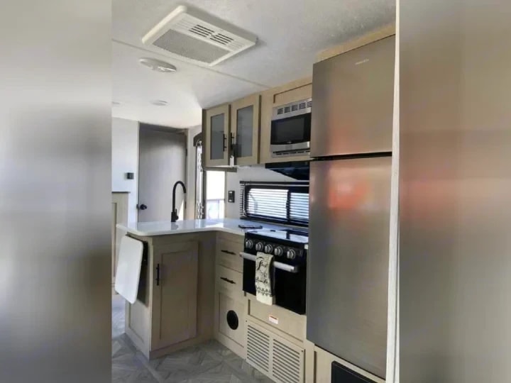 Kitchen with stainless range, microwave, and refrigerator along the wall