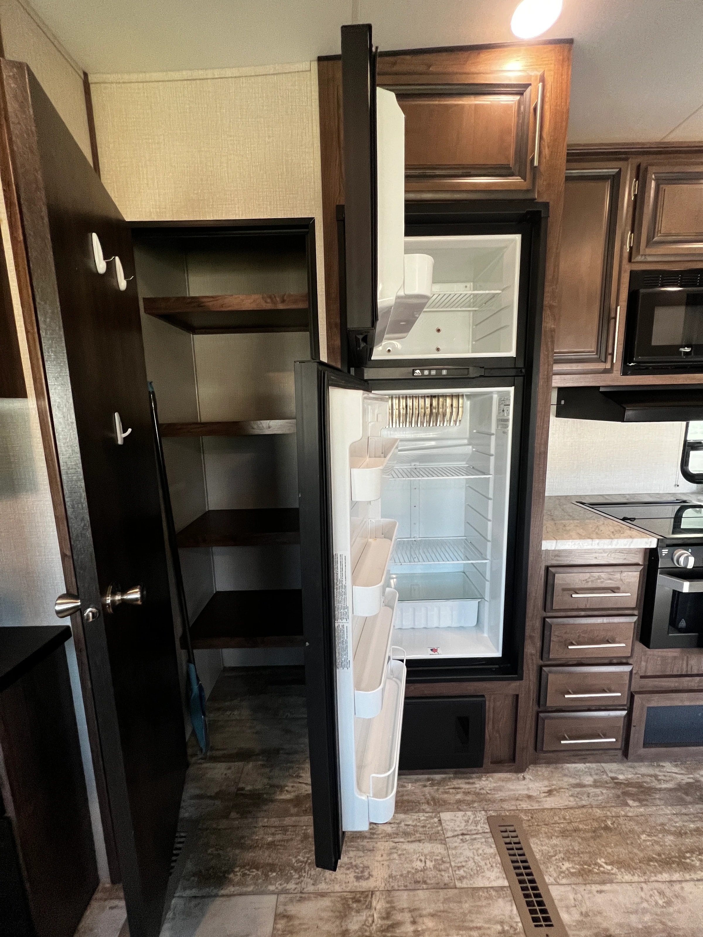 Pantry shelves beside the open refrigerator in the kitchen