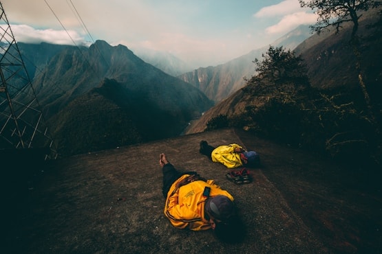 Two campers lying out in sleeping bags on a high ridge at dusk