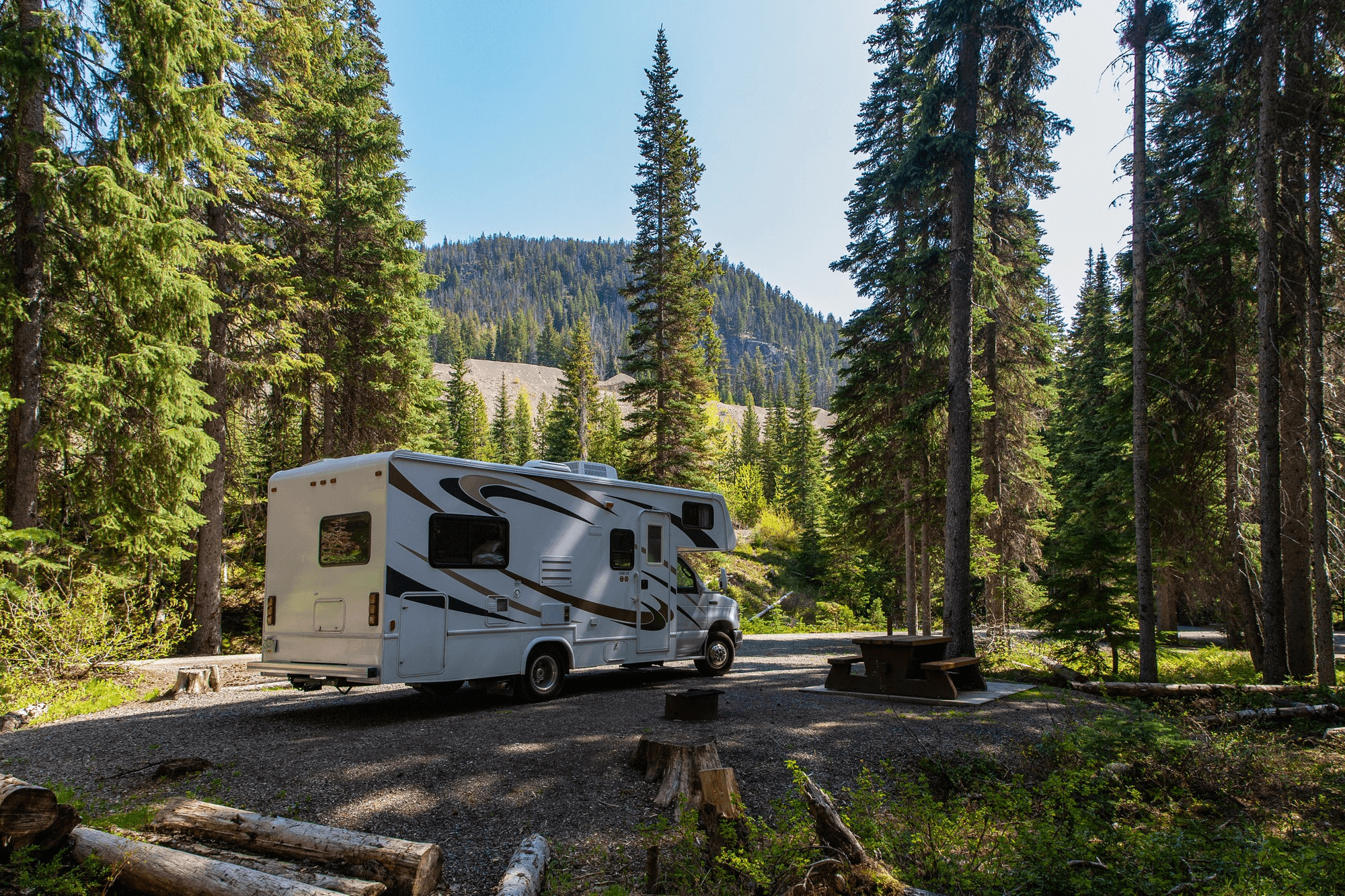 An RV parked at a forest campsite in the mountains